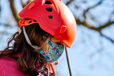 Little girl with protections practicing climbing between trees with ropes and nets