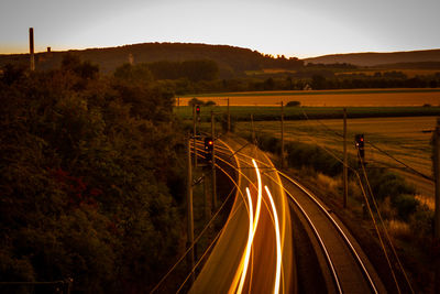 Light trails on road against sky at sunset