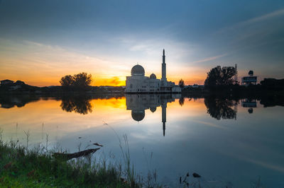 Reflection of mosque on calm lake during sunset