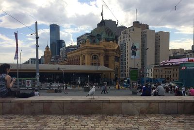 People in city against cloudy sky