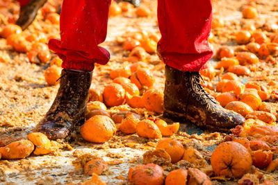 Low section of man standing on messy smashed oranges