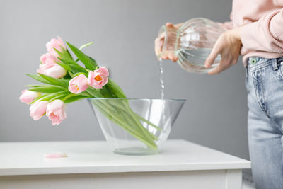 Midsection of man holding flower vase on table