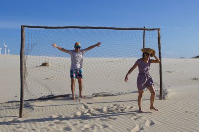 Full length of children playing on beach against sky