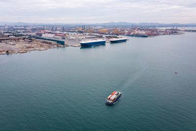 Small container ship sailing in sea and shipping port background photograph aerial view from drone