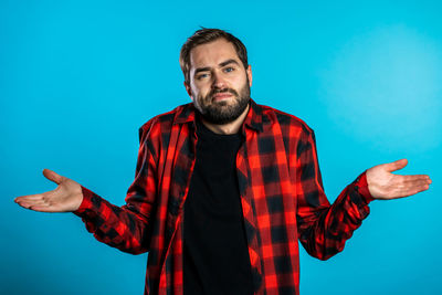 Man with arms raised standing against blue background