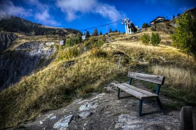 Empty bench on field against sky