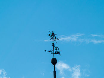 Low angle view of weather vane against blue sky