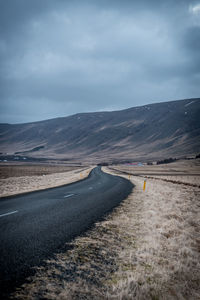 Road leading towards mountain against sky