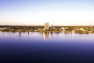 City buildings by river against sky