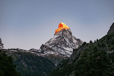 Low angle view of sun shining on mountain against clear sky