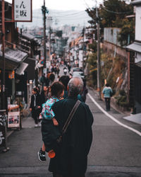 Rear view of people walking on street in city