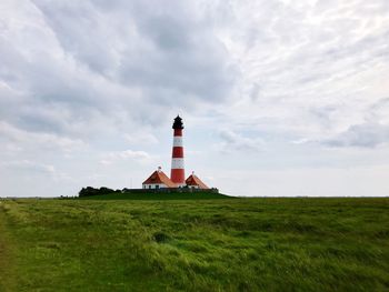 Lighthouse on field against sky