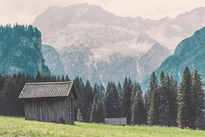 Scenic view of trees and houses on field against mountains