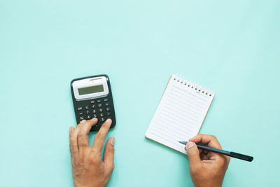 Low section of person holding paper against blue background