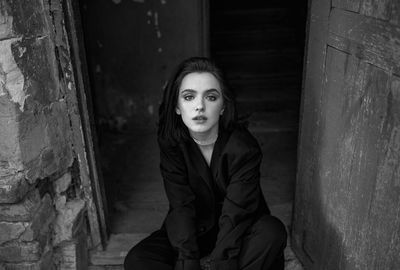 Portrait of young woman sitting on wall