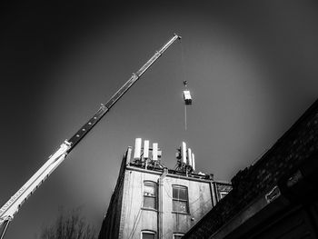 A crane lifting a cell site cabinet onto a building 