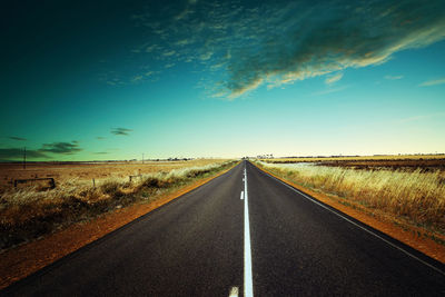 Road amidst field against sky