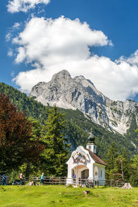 House on field by mountain against sky