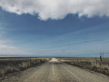 Road amidst field against sky