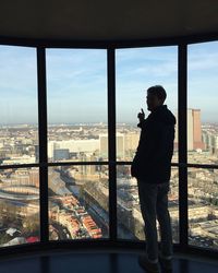 Man standing by window over city