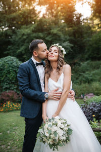 Bridegroom kissing bride at park