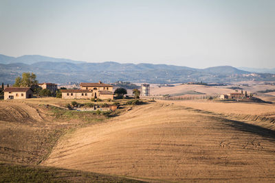 Scenic view of field by buildings against sky