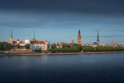 Buildings by river against sky