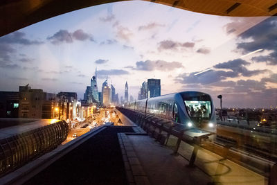 Railroad tracks in city against cloudy sky