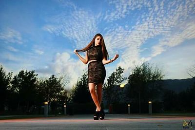 Young woman with umbrella against sky