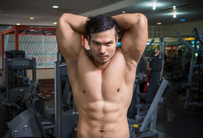 Midsection of shirtless man sitting in kitchen