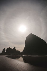 Silhouette mountain by sea against sky during sunset