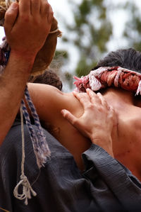 Rear view of people carrying man for crucifix outdoors