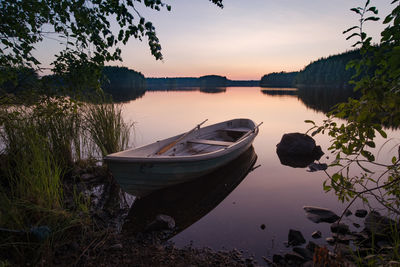 Boats moored in lake against sky during sunset