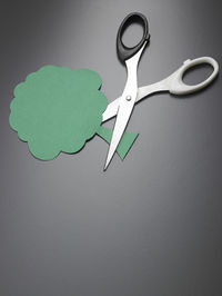 Close-up of scissor and paper tree on gray background