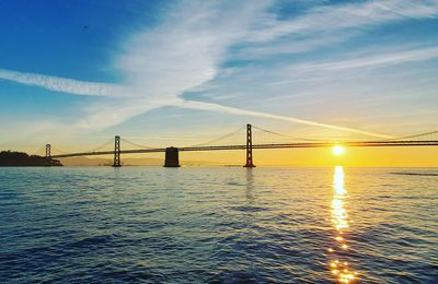 Bridge over sea against sky during sunset