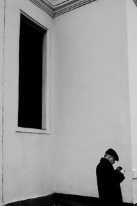 Side view of woman standing against window