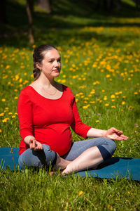 Pregnant woman doing asana sukhasana outdoors