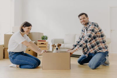 Smiling couple with dog in cardboard box