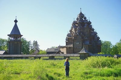 Rear view of man standing on field against building