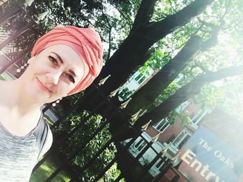 Portrait of smiling young woman against trees