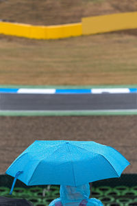 Close-up of wet blue umbrella on road