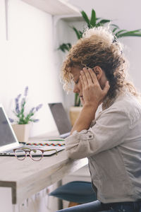 Young woman using mobile phone while sitting on table