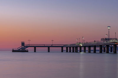 Pier over sea against clear sky during sunset