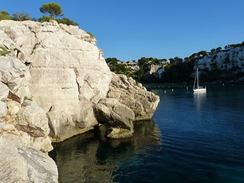 Rock formation by sea against clear blue sky