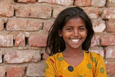 Portrait of young woman standing against brick wall