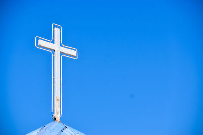 Low angle view of cross sign against clear blue sky