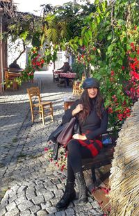 Portrait of young woman sitting on chair against plants