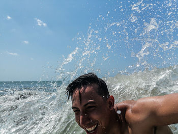 Shirtless man splashing water while swimming in sea