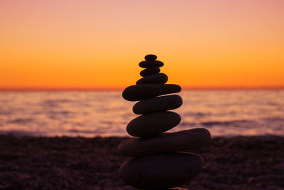 Stack of pebbles on beach during sunset