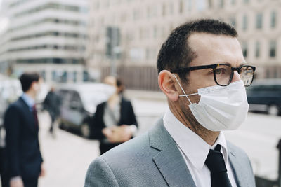 Mature businessman with protective face mask in city